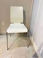 Front view of white chair showing seat, backrest and chrome legs