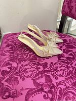 Side view of both heels showing glitter finish, bow embellishment and slingback strap
