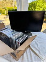 Front view of eMachines monitor next to open box of CDs