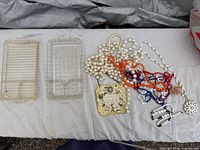 Overall lot view showing glass trays left and assorted necklaces and plaque right