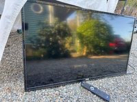Front view of RCA 42" TV with remote in front