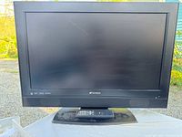 Front view of Sansui TV with remote on stand