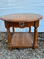 Front view of round side table showing legs, apron cut-out, lower shelf