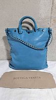 Front view of blue Bottega Veneta tote with dust bag
