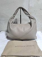 Front view of gray woven leather hobo bag with dust bag