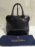 Front view of woven leather handbag with dust bag