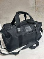 Front angled view showing Coach patch, handles, shoulder strap