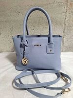 Front view showing Furla logo, top handles, detachable strap and gold hardware