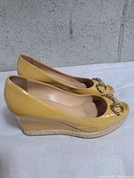 Side profile of both shoes showing patent leather, wedge heel and jute trim