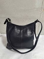 Front view of black leather Roots tote showing overall condition, texture, and strap