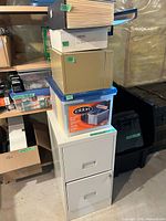 Full view of filing cabinet with file tub, boxes, and hanging folders stacked on top