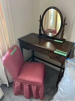 Vanity with attached swivel mirror and pink upholstered chair