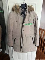 Full view of beige Arctic Expedition parka on hanger