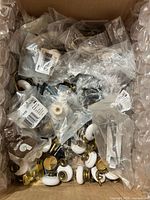 Box showing mixed packaged porcelain knobs, brass fittings and screws