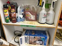 Shelf showing assorted chemicals, two trigger bottles, boxed Woodstream sprayer