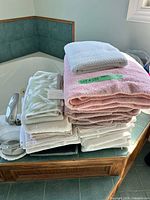 Stacked towels on bathtub ledge showing variety of colors and sizes