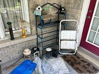 All items grouped on porch: plant rack, step stool, lanterns, tarps, doormat, birdhouse, feeders