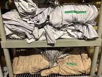 Bundled light gray-silver and beige-tan curtain sets on shelving