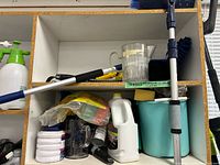 Overview of shelf with spray bottle, bucket, extension pole, measuring pitcher, pads and sponges