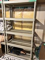 Full view of beige plastic shelving unit with five shelves