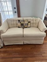 Full front view of striped loveseat with plaid pillow