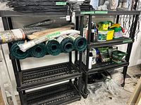 Both black plastic shelving units side by side loaded with garden items