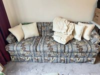 Blue floral sofa with cream slipcover and four throw pillows placed on top