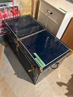 Top and side view of blue metal steamer trunk showing brass-tone hardware and overall condition