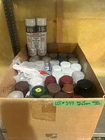 Box containing stacked spray paint cans visible front and sides