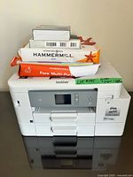Front view of Brother printer with ink, Dell drive box, and stacked Hammermill paper reams