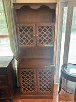Full view of brown wood veneer hutch showing upper and lower lattice doors and open middle shelf