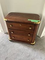 Front view of walnut dresser showing three drawers, brass corners, pulls