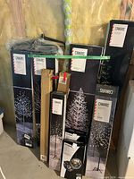 Group of eight boxed LED trees standing against wall
