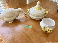 goose figurine, lidded tureen, bowl with bow displayed on table
