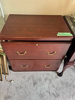 Front view of the cherry 2-drawer lateral file cabinet showing brass handles and lock