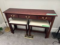 Front view of console table with drawers and two stools stored beneath