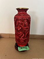 Front view of cinnabar carved lacquer vase on wood stand