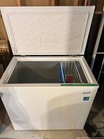 Chest freezer front with lid open showing interior and basket