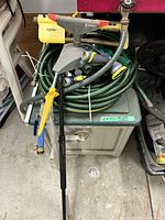 Lot overview including hose hideaway cabinet, coiled hose, sprinklers, nozzles and wands