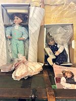 Both dolls inside their original boxes on trunk, accessories visible