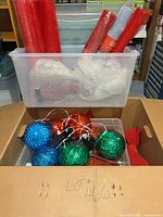 Entire lot in cardboard box showing ornaments, mesh rolls, bows