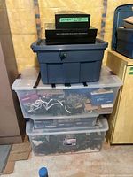 Stacked storage totes containing boxed and loose string lights, small black box on top
