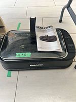 Closed grill with glass lid and manual on top