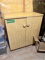 Front view of light wood laminate cabinet with double doors and round knobs