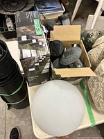 Open box containing bollard light housings, several loose stake lights and an opaque globe