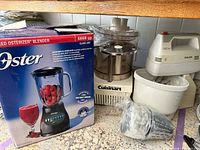 Overall lot showing Oster blender box, Cuisinart processor, Philips mixer and accessories