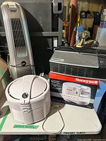 Group shot showing all three appliances: Lasko tower fan, Honeywell humidifier beside original box, and Oreck air purifier