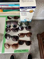 Group of ten sunglasses and lens wipes box