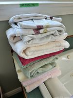 Stack of assorted cotton towels in multiple colours on bathtub