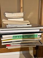 Stack of assorted sketchbooks and pads with loose sheets on top